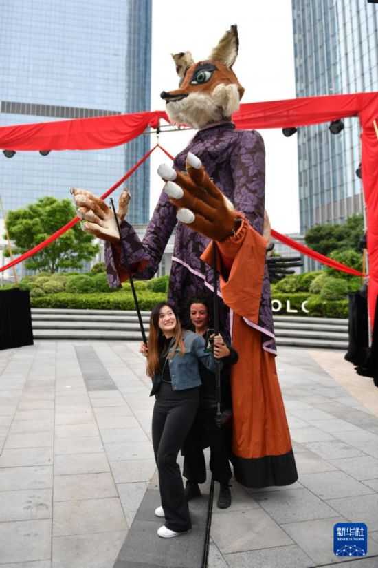 5月7日，在长沙国金中心，观众（左）在演出结束后体验操作大型木偶。新华社记者 陈振海 摄