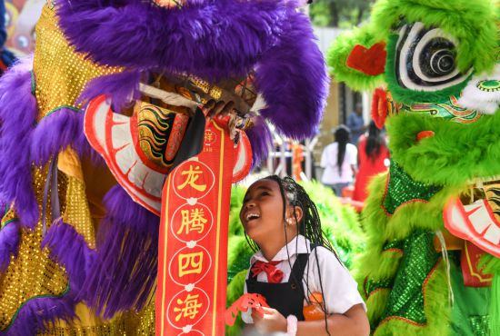 2月7日，小朋友在肯尼亚内罗毕大学孔子学院举行的“龙腾鼓跃闹新春”活动上与舞狮表演队互动。