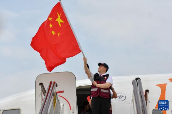 　5月18日，中国政府援缅卫生防疫队队员抵达昆明长水国际机场后，在舱门前挥舞国旗。新华社发（彭奕凯摄）