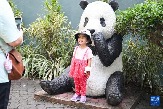 5月17日，在马来西亚吉隆坡的国家动物园，一名小女孩与大熊猫雕塑合影。新华社记者 程一恒 摄