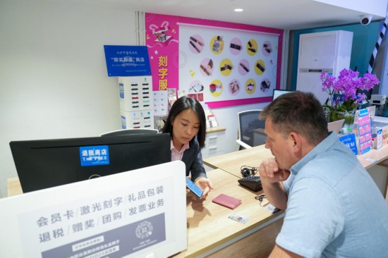 　　2025年4月30日，在北京汉光百货内的退税柜台，工作人员（左）为一名俄罗斯顾客办理离境退税“即买即退”业务。新华社记者 鞠焕宗 摄