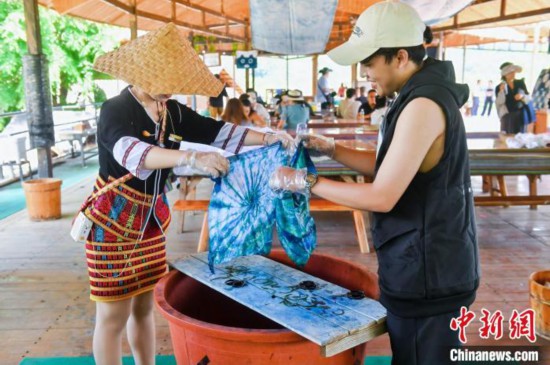6月9日，印尼博主陈浩杰(右一)在海南槟榔谷黎苗文化旅游区体验苗族扎染。(海南省国际文化交流中心 供图)