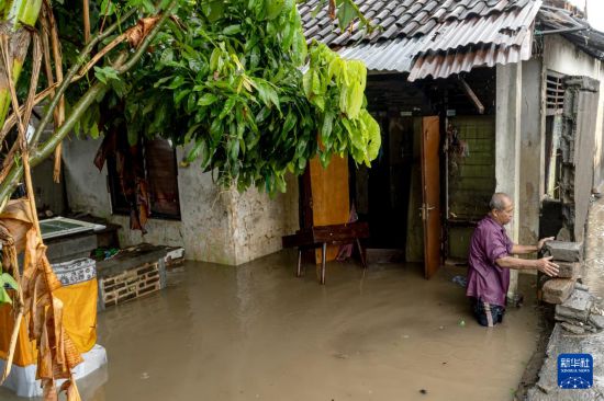 9月10日,在印度尼西亚巴厘岛登巴萨,一名男子站在遭到洪水侵袭的房屋外。新华社发(迪基摄)