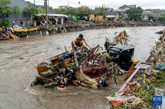 9月10日,在印度尼西亚巴厘岛登巴萨,一名男子蹲在被洪水冲毁的挖掘机上。新华社发(迪基摄)