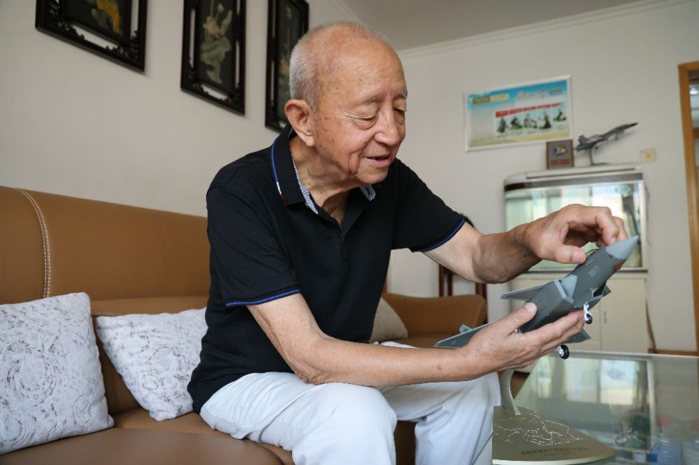 ↑2023年7月24日，新中国第一代遨游员陶伟在家中擦抹歼-20飞机模子。新华社发（张瑞 摄）
