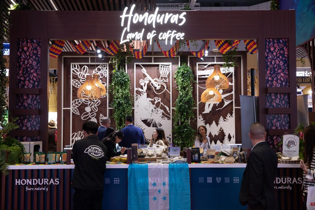 2023年11月6日，参观者在第六届进博会国家展洪都拉斯展台咨询咖啡豆等展品信息。