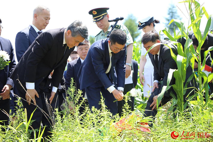 当地时间7月25日，祭扫队伍面向松骨峰的方向，在庄严肃穆的气氛中敬献花束，鞠躬默哀。 人民网记者 刘融摄
