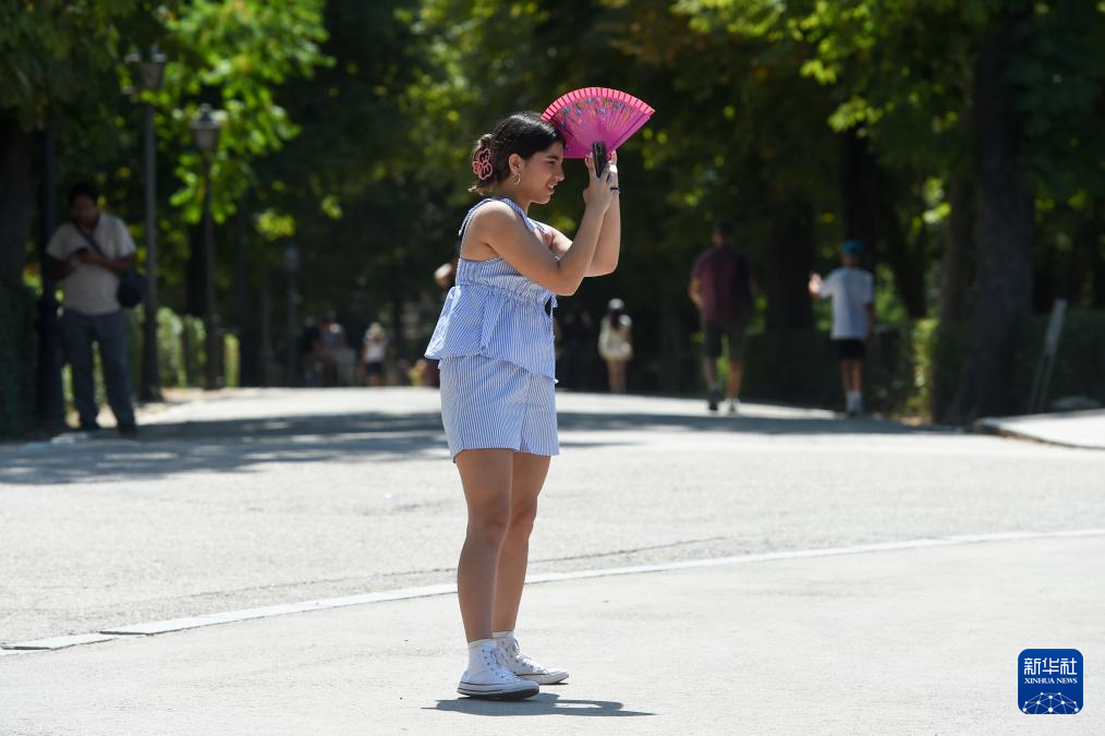 8月4日，一名女子在西班牙马德里的公园内用扇子遮阳。新华社发（古斯塔沃·巴连特摄）