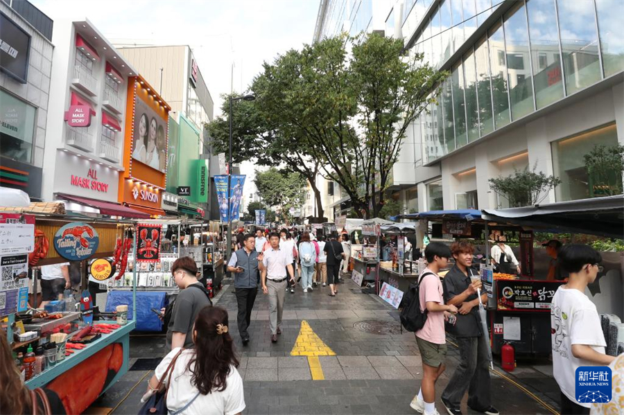 8月6日，游客在韩国首尔明洞商圈游览。新华社记者 姚琪琳 摄