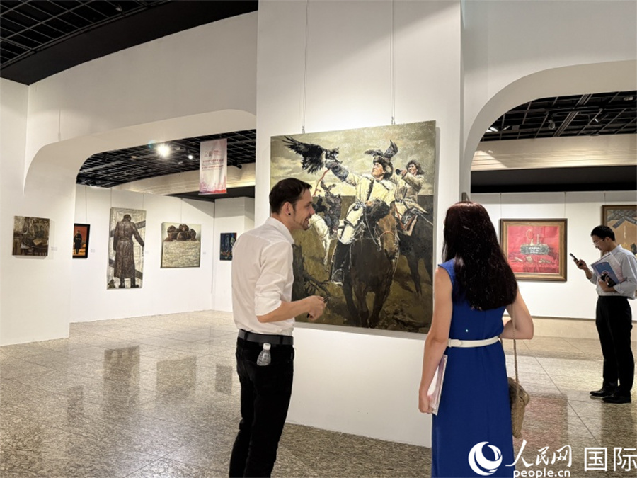 俄罗斯艺术家在展区欣赏画作。人民网记者 杨倩摄