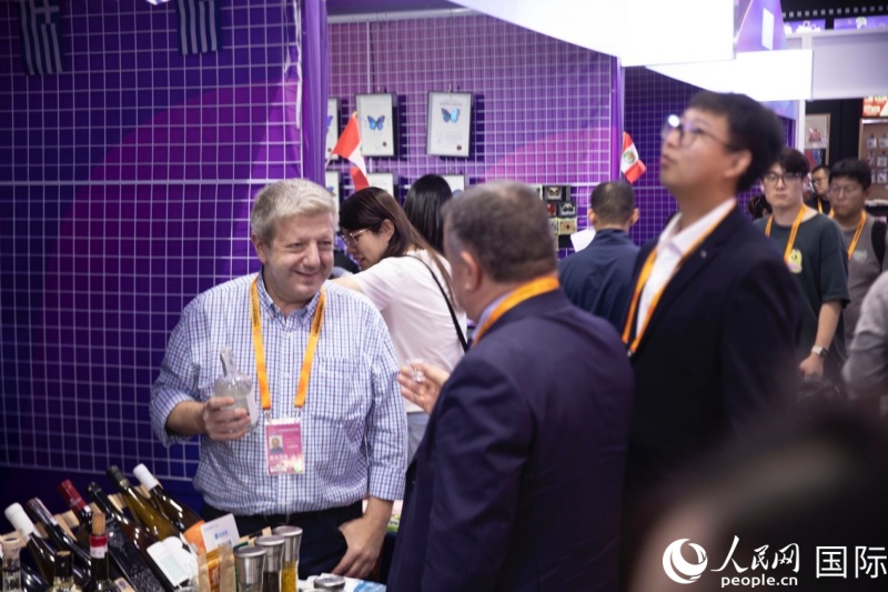 希腊共和国驻华大使馆展区工作人员正在向游客介绍特色酒类产品。人民网 李泽摄