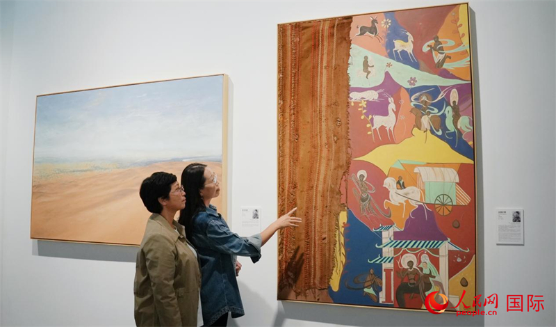 青海油田第一中学退休教师李育勤和王华在博茨瓦纳艺术家托唐画作前观展。人民网 严小晶摄