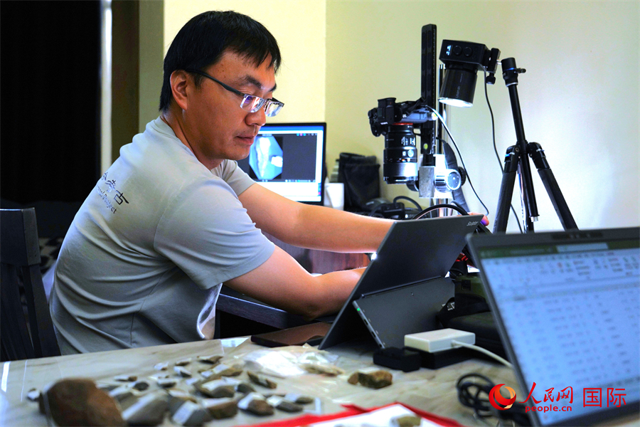 中方现场负责人赵清坡使用自制摄影架拍摄典型石器照片。人民网记者 黄炜鑫摄