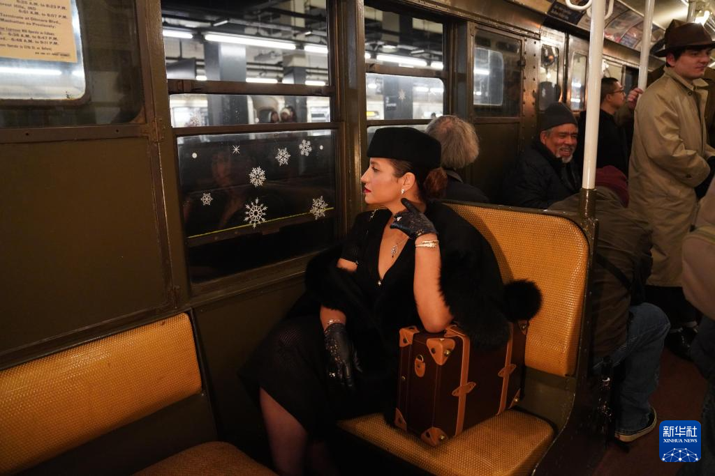 12月14日，在美国纽约，一名女子身着怀旧服饰乘坐“怀旧地铁”。新华社记者 张凤国 摄