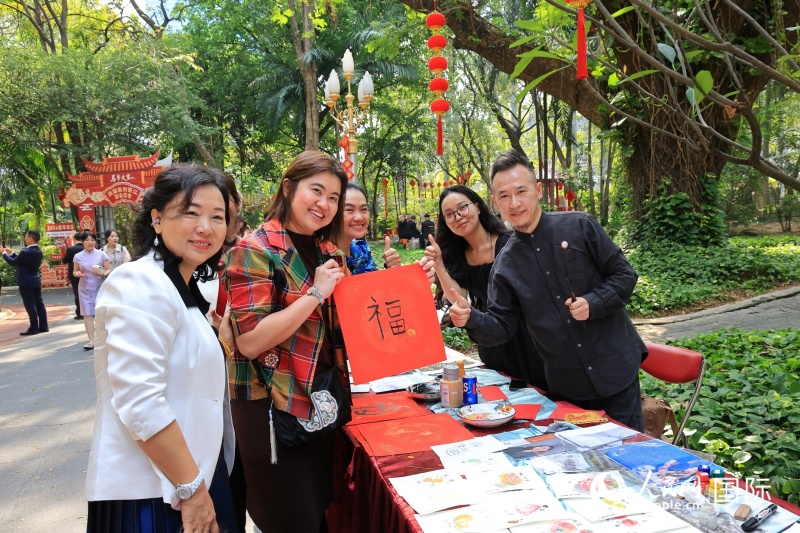 参加春节招待会的泰国友人展示现场创作的书法作品。(白元琪摄)