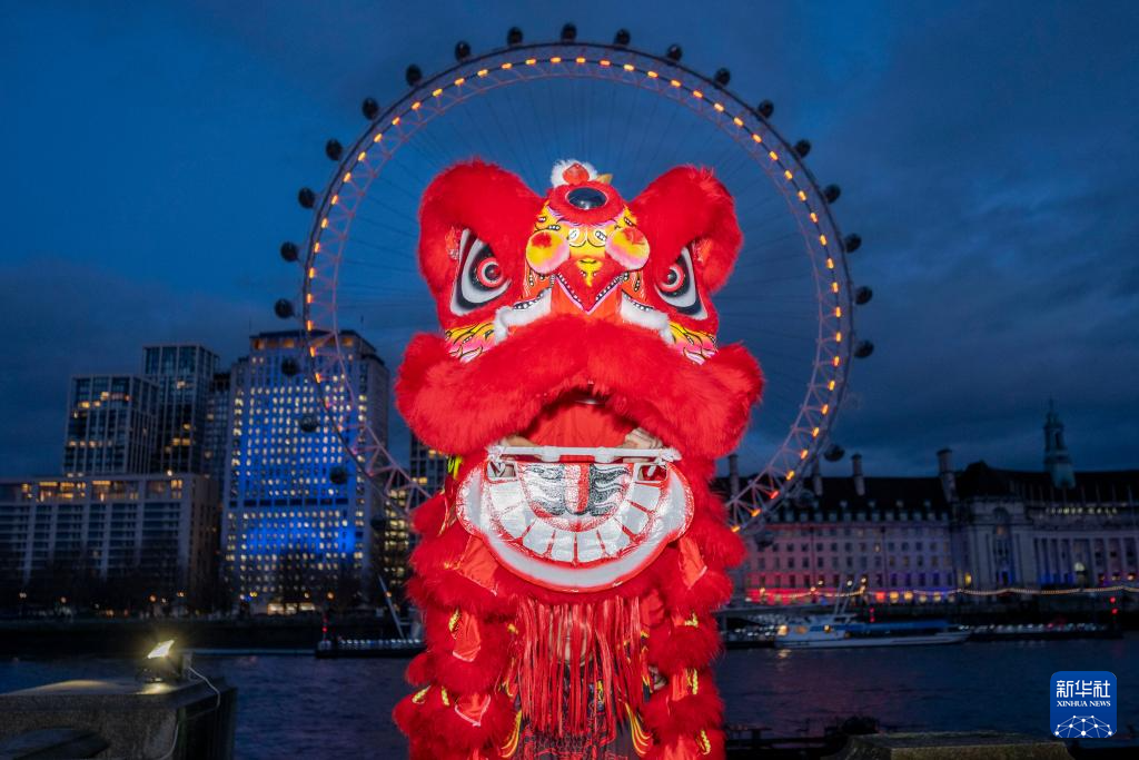 2月16日晚，在英国首都伦敦，演员在亮起红色灯光的“伦敦眼”前表演舞狮。新华社发（史蒂芬·程摄）
