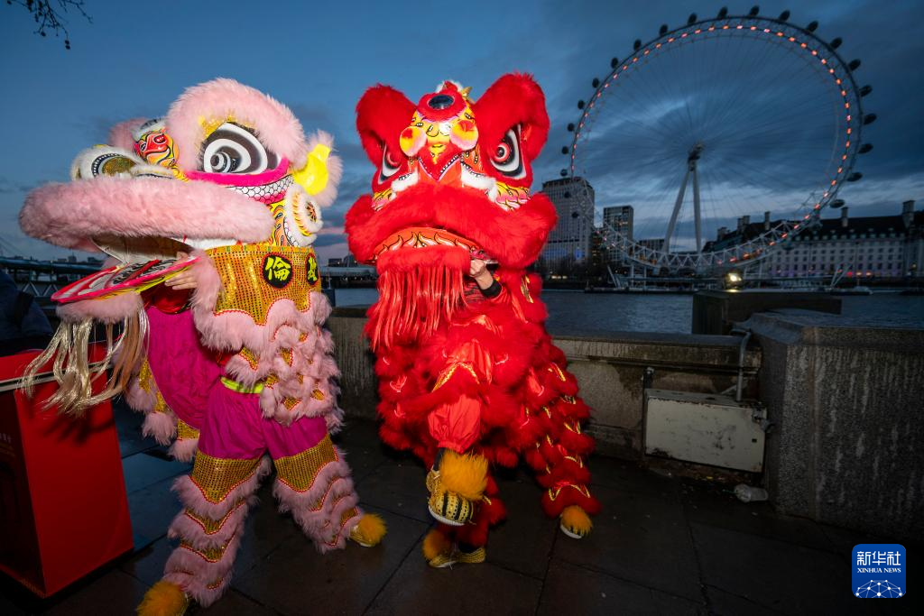 2月16日晚，在英国首都伦敦，演员在亮起红色灯光的“伦敦眼”前表演舞狮。新华社发（史蒂芬·程摄）