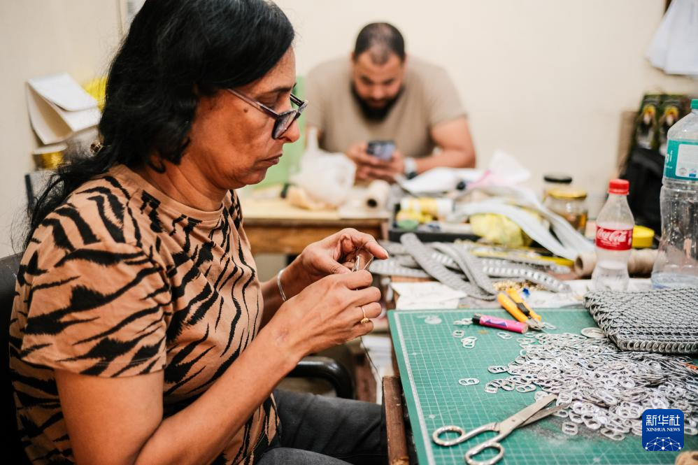4月21日，在位于埃及开罗“垃圾城”的手工作坊内，工作人员用易拉罐拉环制作环扣包。