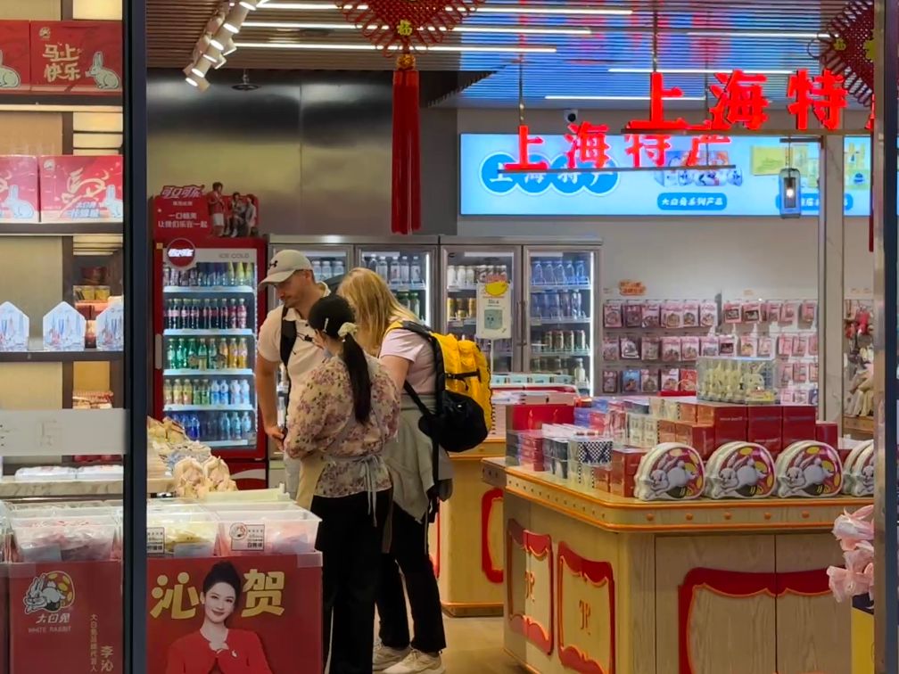 国庆假期,外国游客在上海虹桥火车站内购买上海特产。新华社发(陈晨 摄)