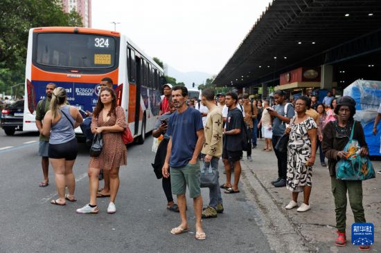 10月28日，巴西警方在里约热内卢展开针对黑帮“红色司令部”的大规模剿匪行动，受公交线路绕行影响，乘客在街边等待。新华社/巴西通讯社