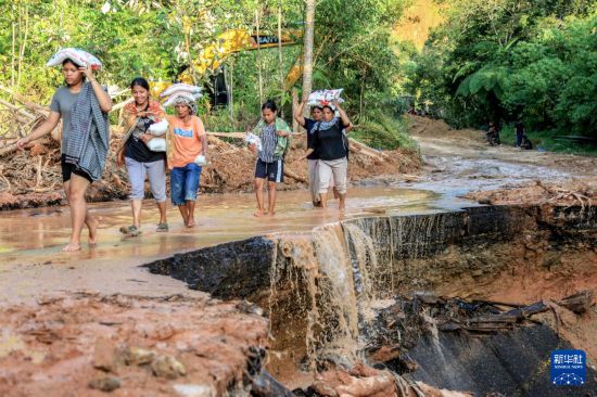 12月2日,在印度尼西亚北苏门答腊省北打巴努里,当地居民搬运救援物资。新华社发(阿尔贝特·达马尼克摄)