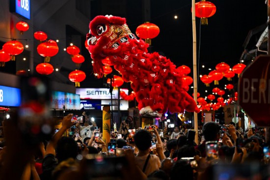 2026年2月21日，在马来西亚槟城州首府乔治市，人们观看舞狮表演。新华社记者 程一恒 摄