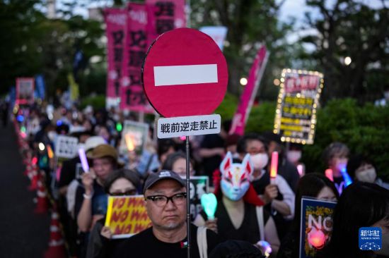 5月19日,在位于日本东京的国会议事堂前,民众手持标语参加抗议集会。新华社记者 贾浩成 摄