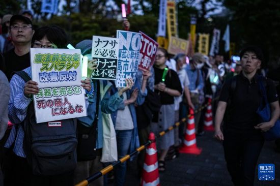 5月19日,在位于日本东京的国会议事堂前,民众手持标语参加抗议集会。新华社记者 贾浩成 摄