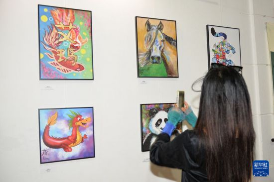 　　6月19日，在克罗地亚萨格勒布，一名女子参观克罗地亚14岁学生艾玛·杜伊莫维奇个人“艺术与书法展”。展出的近50幅绘画和书法作品中包含龙舟、粽子、大熊猫、中秋节等中国传统文化元素。新华社记者 马震 摄