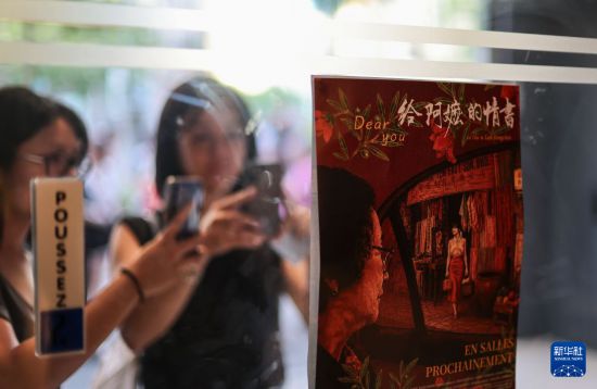 7月5日,在法国巴黎,人们拍摄中国电影《给阿嬷的情书》的海报。新华社记者 邬惠我 摄