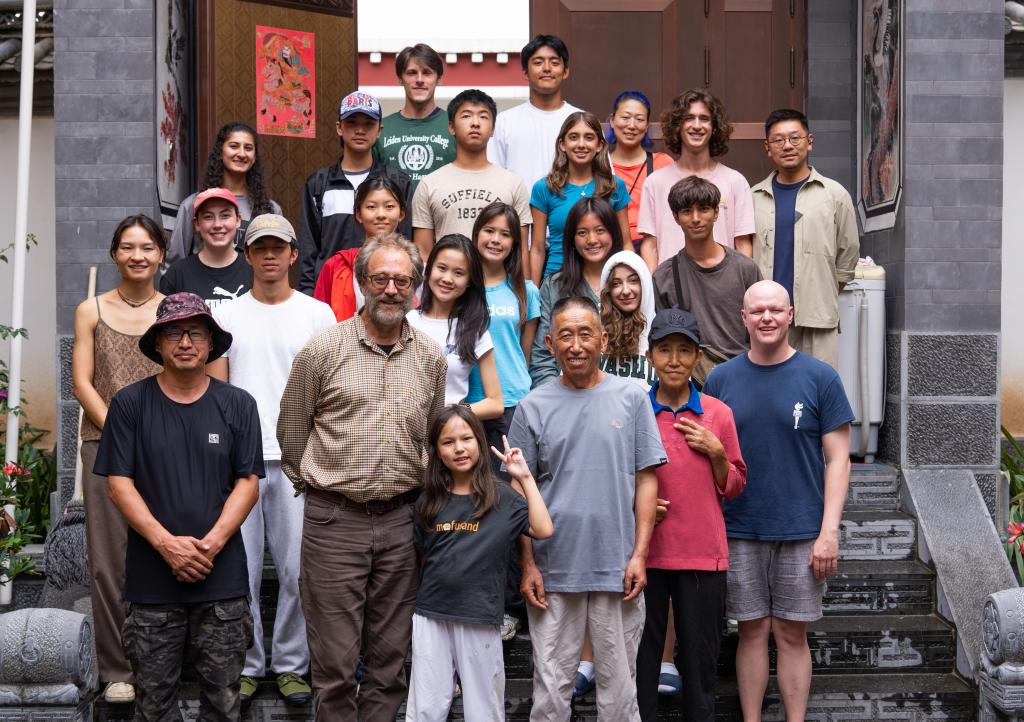 7月26日，在云南省迪庆藏族自治州德钦县燕门乡茨中村一户村民家中，约翰·弗劳尔（前排左二）与美国青少年团队同村民（前排右二、右三）合影。新华社记者 高咏薇 摄